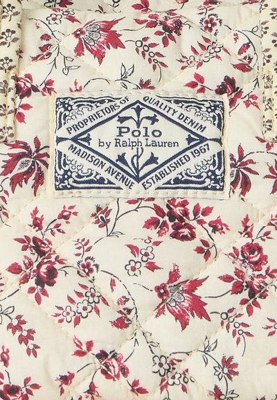 Siūtas audinys su kreminio fono su raudonos ir juodos spalvų gėlių raštu. Yra mėlynas „Polo by Ralph Lauren“ etiketė.