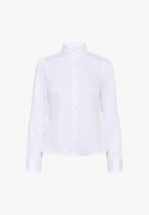 Chemise blanche à manches longues en coton avec un col haut, à volants et un fermoir à boutons sur le devant. Dotée de poignet à boutons avec des accents à volants.