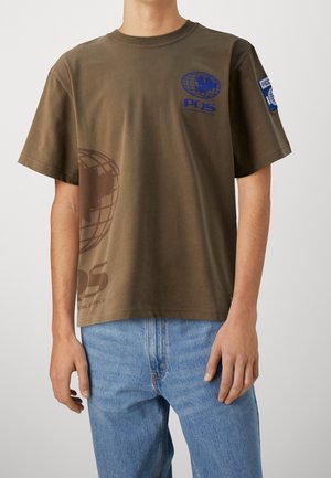 Camiseta de algodón color verde oliva con un gráfico de un globo y un logo en marrón y azul en el pecho, de mangas cortas y con un corte relajado.