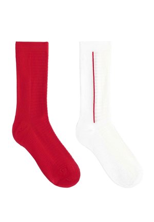 Un șoset roșu și unul alb cu o dungă verticală subțire roșie, ambele cu model nervurat și lungime medie, arătate unul lângă altul pe un fundal alb.