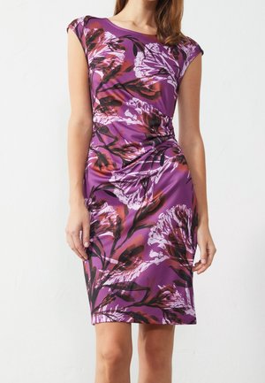 Vestido morado sin mangas hasta la rodilla con patrón floral abstracto en negro, rojo y blanco, usado por una mujer de pie con cabello castaño.