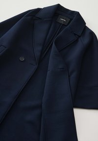 Marineblauer Blazer aus glattem Stoff mit Reverskragen, Ein-Knopf-Verschluss und zwei Fronttaschen.