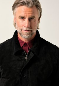 Svart mockajacka med knapp- och dragkedjestängning, med hög krage och en rik bordeauxskjorta under. Slät textur och skräddarsydd passform.