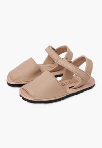 Sandali in pelle beige con design a punta quadrata, cinturino alla caviglia e suola in gomma nera. Presentano dettagli di cucitura e una texture liscia.