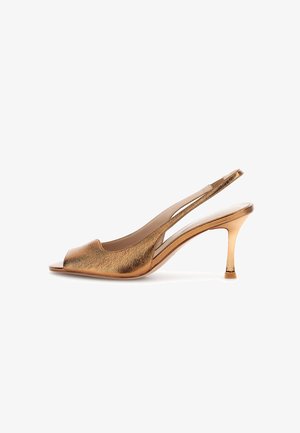 Bronzový kovový otevřený sandál s páskem kolem paty a tenkým středně vysokým podpatkem na bílém pozadí.