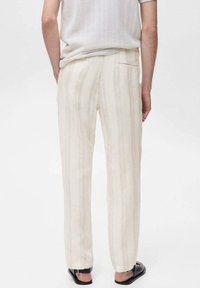 Pantalons rayés beige clair avec une coupe droite, fabriqués à partir d'un tissu texturé. Ils disposent d'une poche arrière et d'un design de ceinture simple.