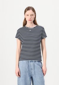 Camiseta a rayas en azul marino y blanco hecha de algodón suave, con un cuello redondo y mangas cortas, presentada con pantalones de corte relajado en azul claro.