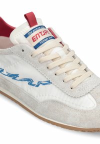 Baskets en daim blanc et gris avec lacets beige, languette de talon rouge, logo latéral bleu, et étiquette indiquant "ENTJPN Vintage Soul" sur la languette.