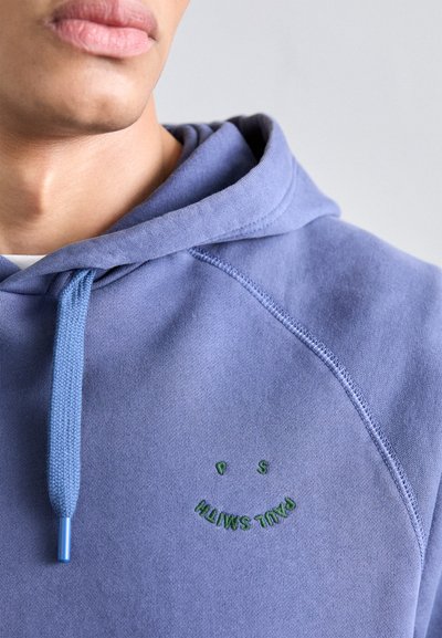 Hoodie lilás claro feito de tecido suave, com bolso frontal, capuz com cordão e detalhe bordado de sorriso verde.