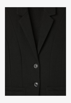 Blazer nero con revers a punta, dotato di chiusura a due bottoni, tessuto strutturato e due tasche frontali. Dettagli delle cuciture verticali visibili.