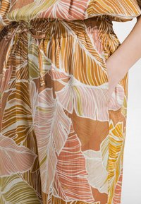 Spódnica w kwiatowy wzór w ciepłych odcieniach pomarańczu, różu i zieleni. Posiada elastyczną talię z wiązaniem i boczne kieszenie, wykonana z lekkiego materiału.