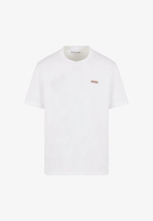Camiseta de algodón blanca con un pequeño parche de logotipo rojo y blanco en el pecho. Cuello redondo clásico y mangas cortas. Textura suave.