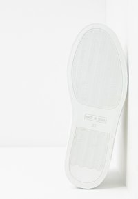 Semelle de chaussure blanche avec motif ondulé antidérapant, marquée "Made in Spain" et taille 37, photographiée sur fond blanc.
