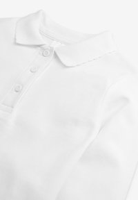 Polo shirt bianco in cotone con colletto scallop, patta con tre bottoni e tessuto testurizzato. Superficie liscia con un design classico.