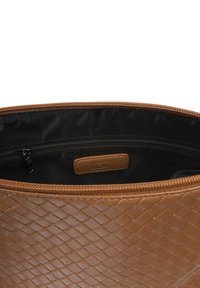Sac en cuir tissé tan avec une surface texturée, doté d'un intérieur doublé noir et d'une fermeture éclair. Comprend une petite étiquette de marque.