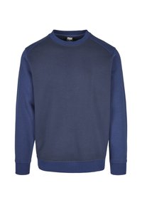 Tumesinist värvi dressipluus ümarate kaeluse, soonikkoes varrukaotste ja äärega. Omab sujuva tekstuuriga kontrastseid paneele õlgadel.