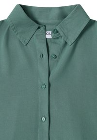 Chemise verte à manches courtes avec un col classique, deux boutons à l'avant et une texture en tissu lisse et léger.