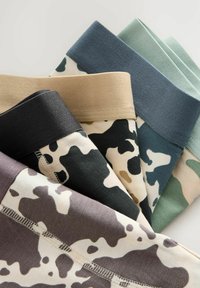 Cinq paires de leggings pliés à motif camouflage avec des ceintures unies aux tons vert pastel, bleu, beige, noir et gris.