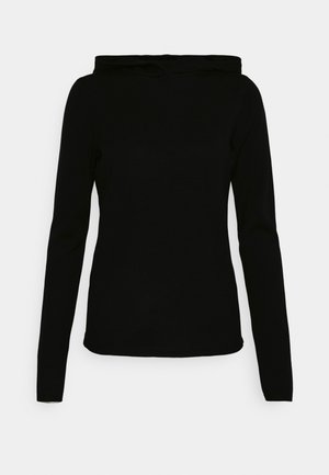 Haut noir à manches longues, ajusté, avec un col bateau haut et une texture lisse et unie sur un fond clair uni.