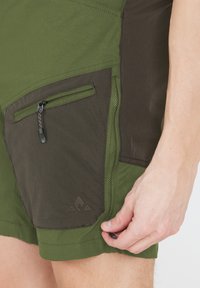 Grønne udendørs shorts med et mørkegrønt panel, lynlåslomme, tekstureret stof og justerbar snoretræk i kanten for en sikker pasform.