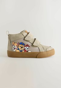 Beige High-Top-Schuhe mit zwei Klettverschlussriemen, einer strukturierten Oberfläche und einer Gummisohle, auf deren Außenseite Cartoon-Hunde gedruckt sind.
