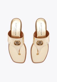 Ciabatte flip-flop tono oro con una parte superiore lucida, caratterizzate da un accento circolare decorativo, forma della punta quadrata e una soletta liscia.