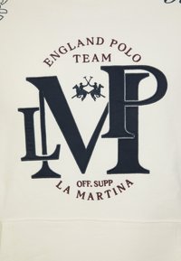 Cream-colored hoodie featuring navy blue embroidered "MVP" initials, crossed polo mallets, and "England Polo Team" text in burgundy.