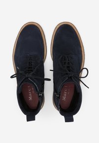 Botas de tobillo de ante azul marino con cordones planos, suela de goma y un acabado texturizado. Presenta una suela marrón contrastante y detalles de cuero.
