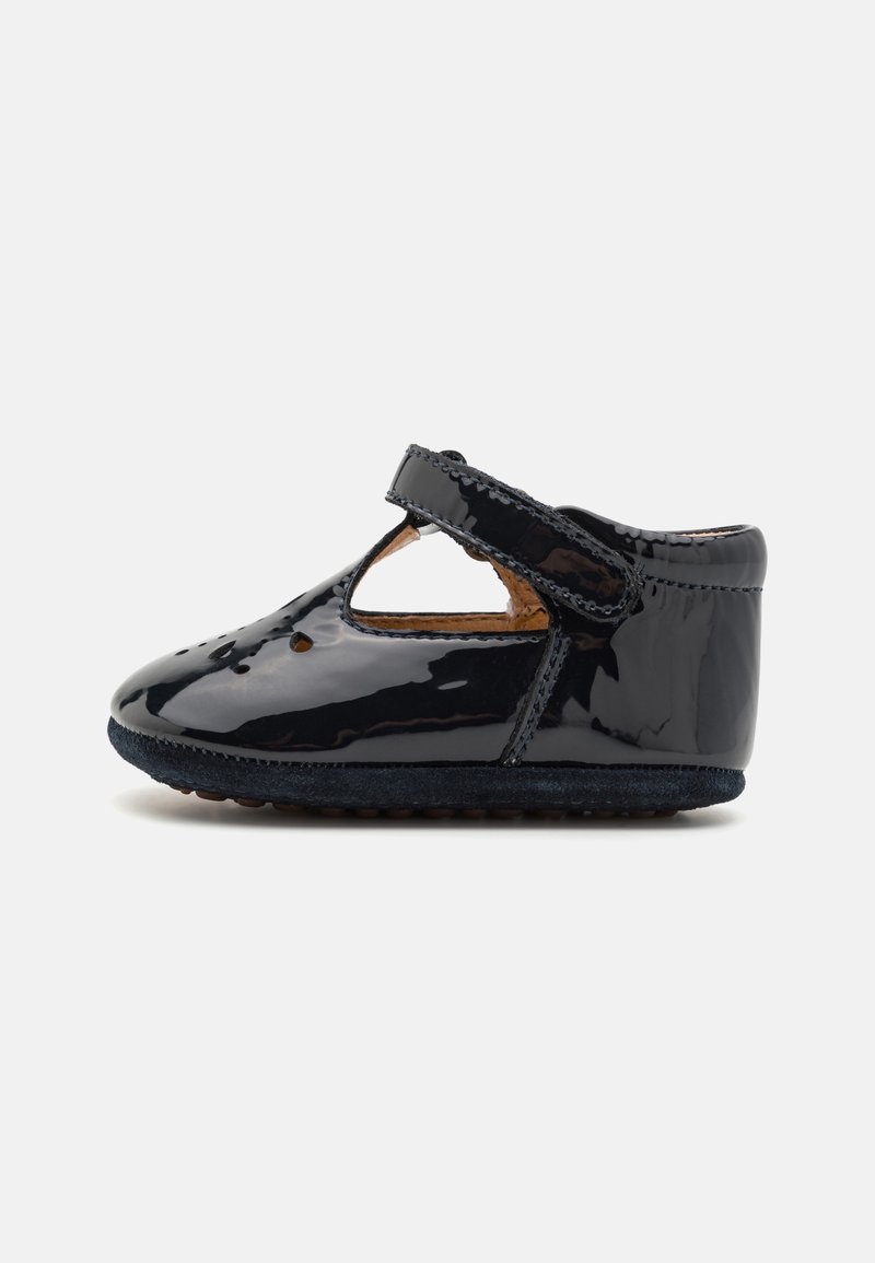 Chaussure de bébé noire brillante avec un bout arrondi, fermeture à bride en T et petites perforations sur le dessus, vue de côté sur fond blanc.