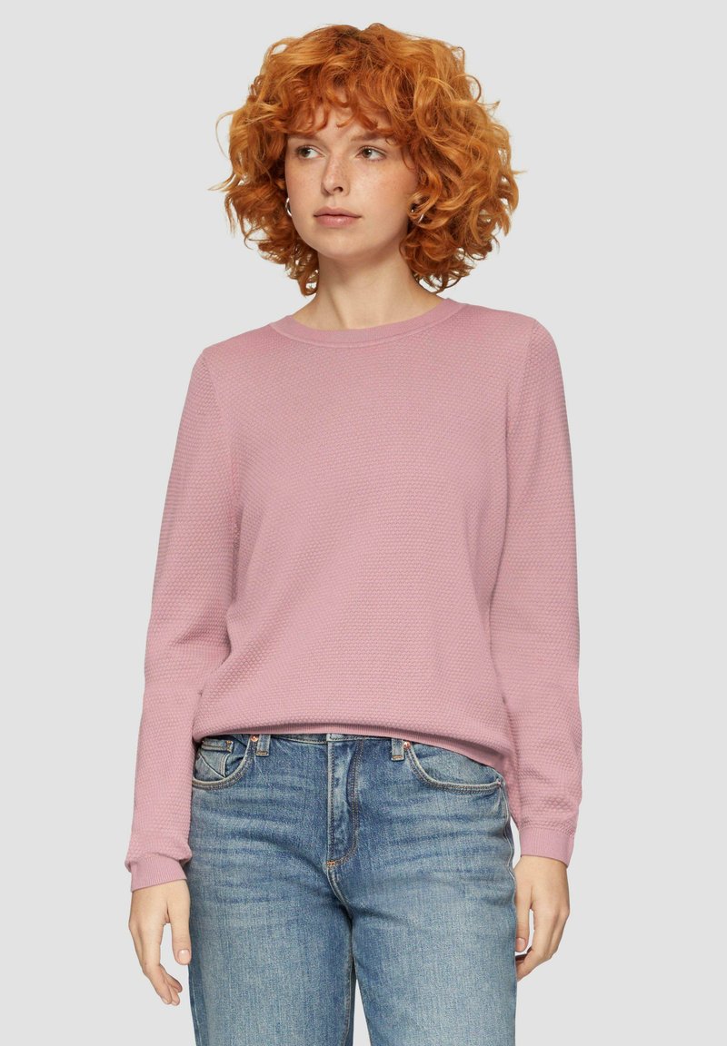 Lichtroze trui met een gestructureerd breiontwerp, ronde halslijn en lange mouwen. G gedragen met blauwe jeans, wat een ontspannen pasvorm laat zien.
