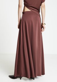 Langes braunes Kleid mit engem Oberteil und weitem Rock. Es hat Schnürungen am Rücken und einen seitlichen Ausschnitt, gefertigt aus einem glatten Stoff.