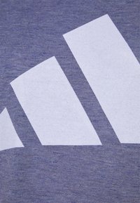Trois bandes diagonales blanches sur un fond de tissu bleu texturé, ressemblant à un détail de logo d'une marque de sportswear.
