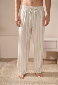 Pantalon de nuit en lin avec une taille élastique et un cordon, présentant des rayures verticales crème et marron clair, texture lisse.