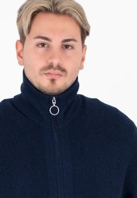 Maglione zip-up a coste di colore blu navy con colletto alto e zip con anello in argento, dotato di un motivo a maglia testurizzata e vestibilità standard.