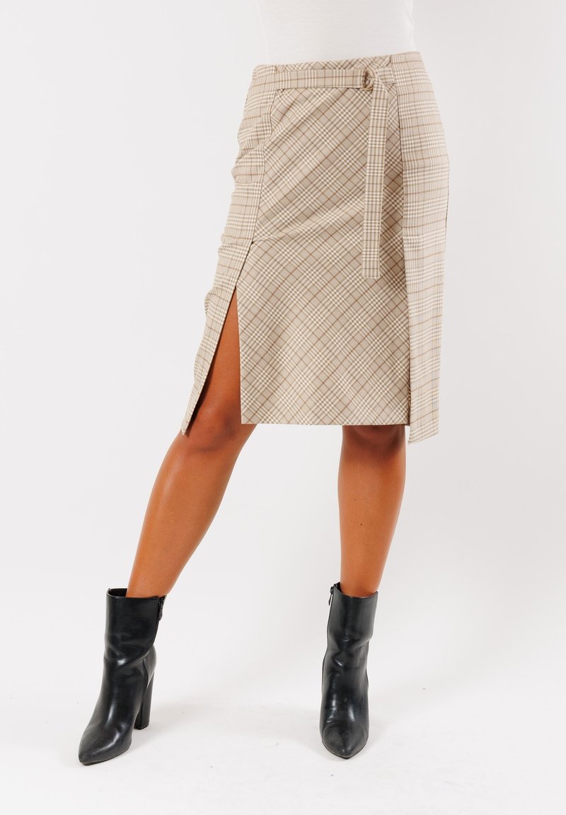 Gonna a tubino in plaid beige con spacco laterale e vita con cintura. Tessuto liscio e silhouette aderente. Indossata con stivali neri alla caviglia.