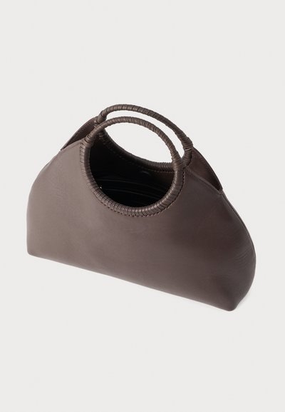 Καφέ δερμάτινη τσάντα χειρός με στρογγυλεμένες, τυλιγμένες λαβές και ελαφρώς καμπυλωτή, φαρδιά βάση σε ουδέτερο φόντο.