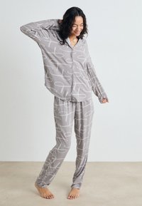 Ensemble de pyjama gris clair avec des motifs abstraits blancs. Le haut a un design à boutons, et le pantalon dispose d'une taille élastique. Texture de tissu douce.
