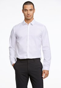 Witte lange mouw met knoopsluiting overhemd gemaakt van gladde stof, met een klassieke kraag en rechte manchetten, gecombineerd met donkere nette broek.