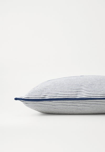 Stačiakampis pagalvė su baltais ir tamsiai mėlynais dryžiais. Ji turi matomą mėlyną apvadu aplink kraštą ir minkštą audinio tekstūrą.