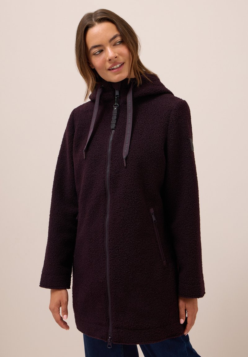 Manteau en polaire violet avec une fermeture éclair à l'avant, une capuche et des cordons de serrage. Comprend des poches latérales et un tissu texturé. Coupe décontractée avec des manches longues.