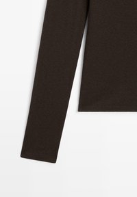 Dunkelbraune langärmelige Strickstoffdetails an Ärmeln und Saum vor einem weißen Hintergrund, der Textur und Nähte zeigt.