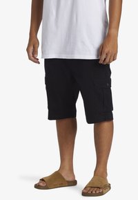 Zwarte cargoshorts met zijzakken, van katoen, met een omgeslagen zoom, gecombineerd met bruin slip-on sandalen met een gestructureerde band.