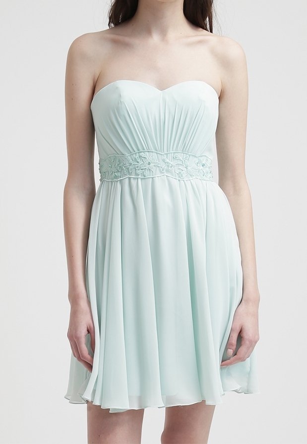 Robe bleu clair sans bretelles jusqu'aux genoux avec corsage plissé et ceinture brodée portée par une femme debout sur un fond uni.