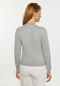 Pulover gri, ușor, cu o textură netedă, mâneci lungi și decolteu rotund, având un model discret cu dungi verticale.