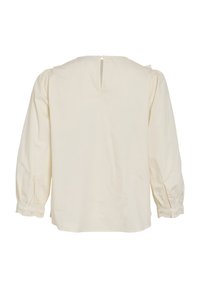 Blouse en coton couleur crème avec une coupe droite, des manches bouffantes douces, un délicat bord en dentelle aux poignets et une fermeture en trou de serrure dans le dos.