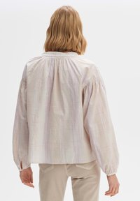 Blusa leggera a quadri pastello con maniche lunghe a palloncino, scollatura arricciata e fessure laterali. Tessuto morbido con una leggera texture.