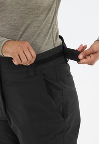 Zwarte broek met een verstelbare tailleband met haak-en-lus, een soepele stoftextuur en zijzakken, gericht op functionaliteit en pasvorm.