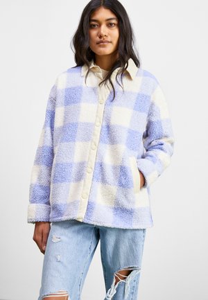 Blue and white checkered fleece jacket with a button-up design, large collar, and side pockets. Worn with distressed blue jeans.