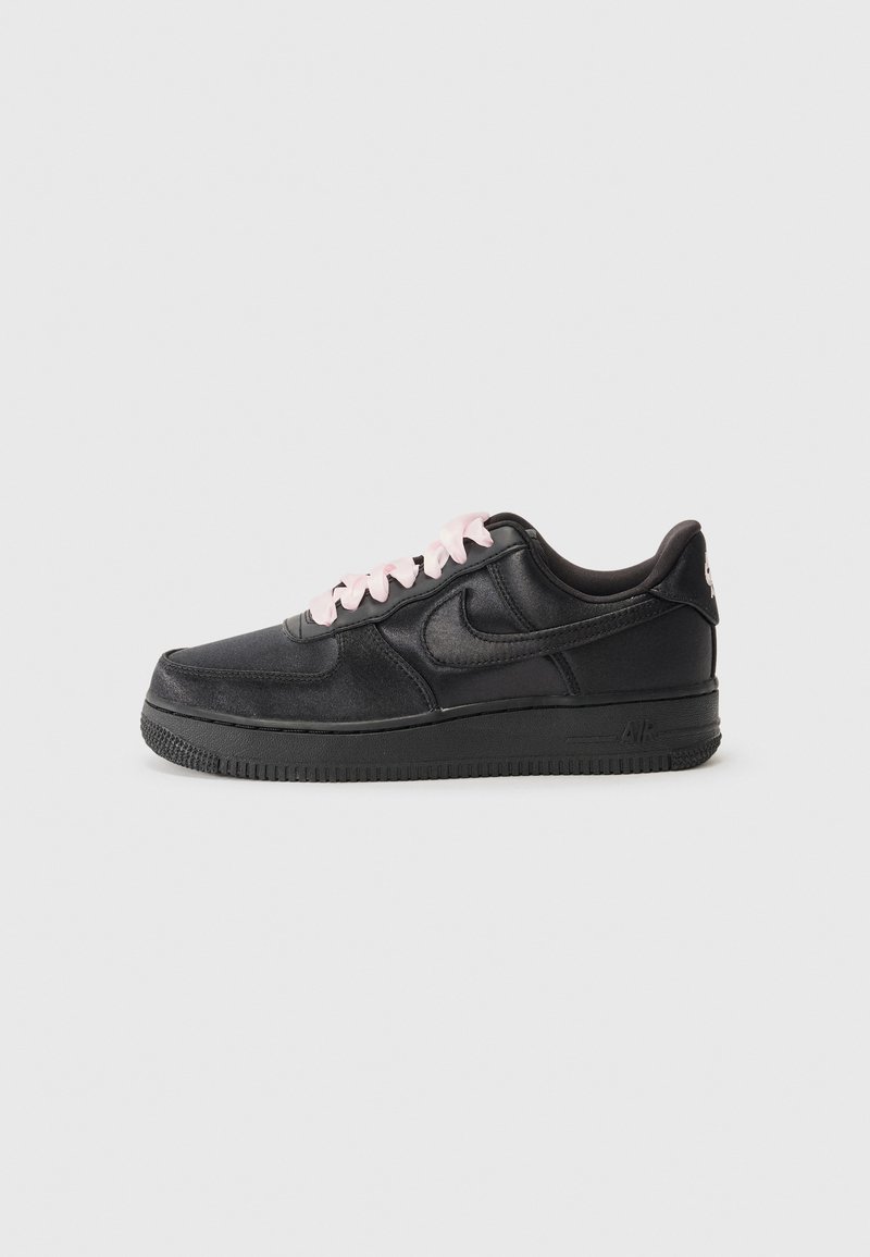 Fekete sneaker sima bőr külsővel, kontrasztos rózsaszín fűzőkkel, lapos gumitalppal és dombornyomott logóval a sarkán.
