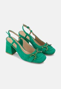 Decollete slingback verde in suede con tacco grosso, punta arrotondata e un'ornamentazione decorativa a gemma verde sulla parte frontale.